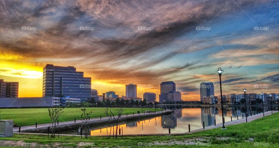 Scenic view of buildings near pond during sunset