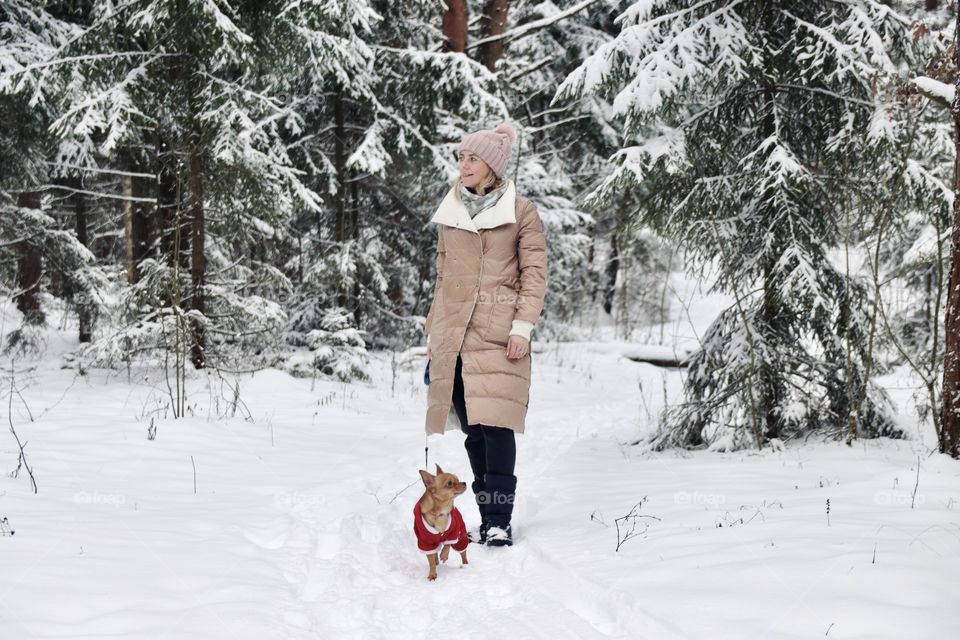 woman walking with dog in snowy forest