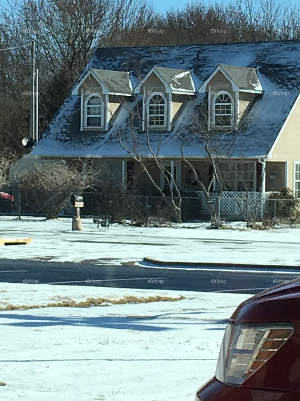 A house with snow a top the roof and on the ground. Quickly melting away. Already gone off road.