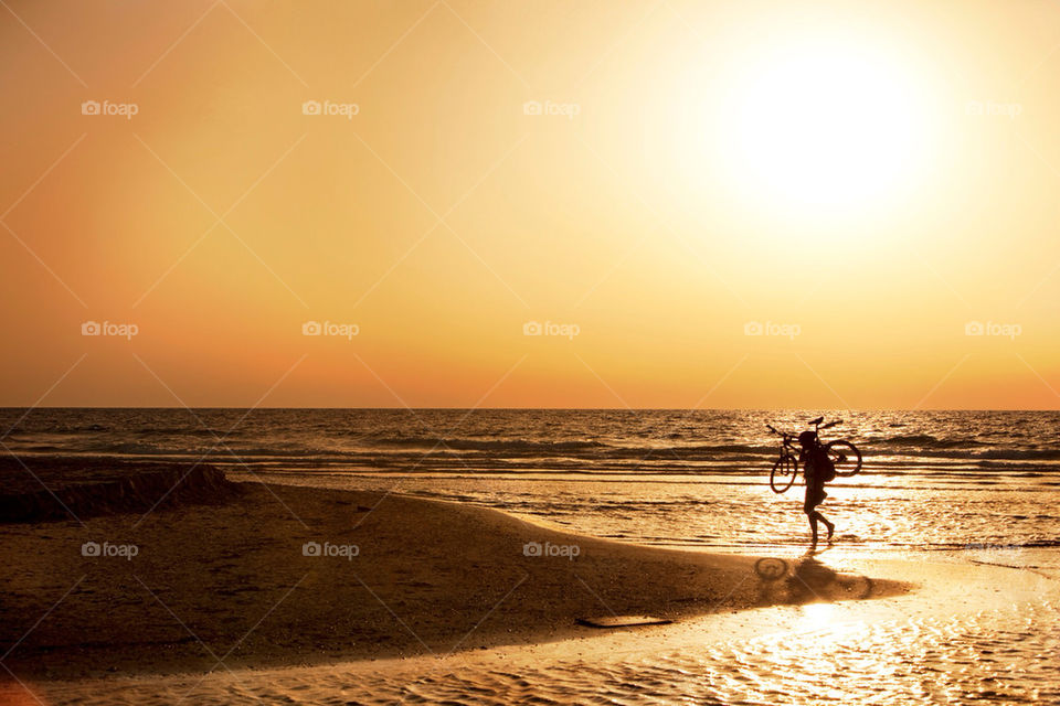 A person carrying bicycle on beach