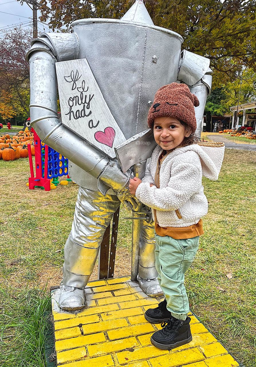 Toddler girl gives tin man a hug, if I only had a heart, tin man from wizard of oz, little girl shows love in a pumpkin patch, pumpkin patch love 