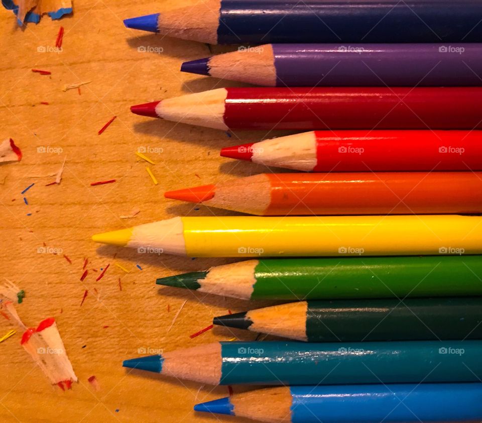 Row of pencil crayons from the colour wheel with pencil shavings
