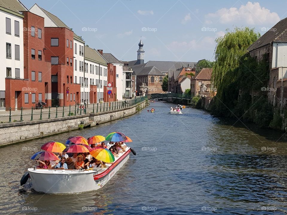 Les parapluies deviennent des parasols, s'adaptant selon le temps ; multicolores, ils illuminent la sobriété de l'architecture urbaine locale et l'ambiance du lieu