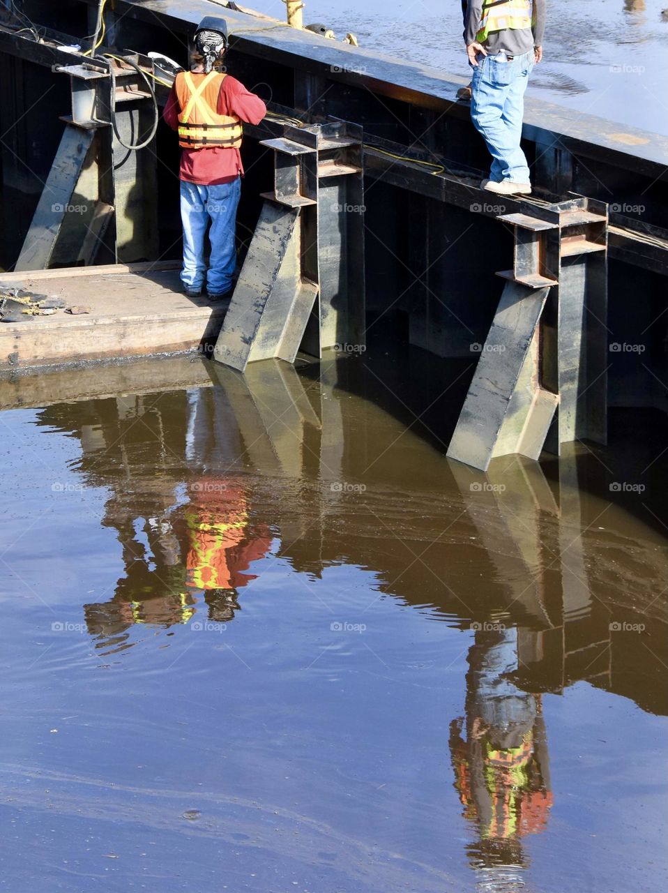 Blue collar worker with his reflection in the water doing construction 