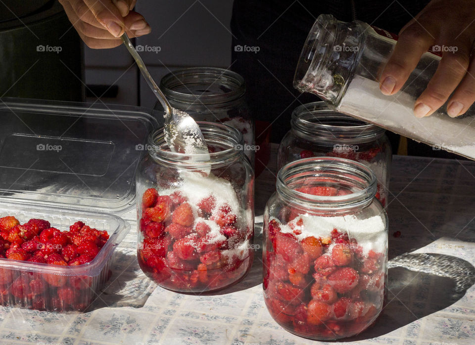 Prepares raspberries with sugar, sweet dessert in jars