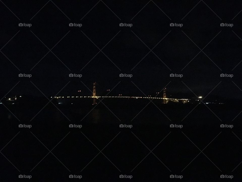 California landmark Golden Gate Bridge in San Francisco end to end lit up at night. Mostly dark.