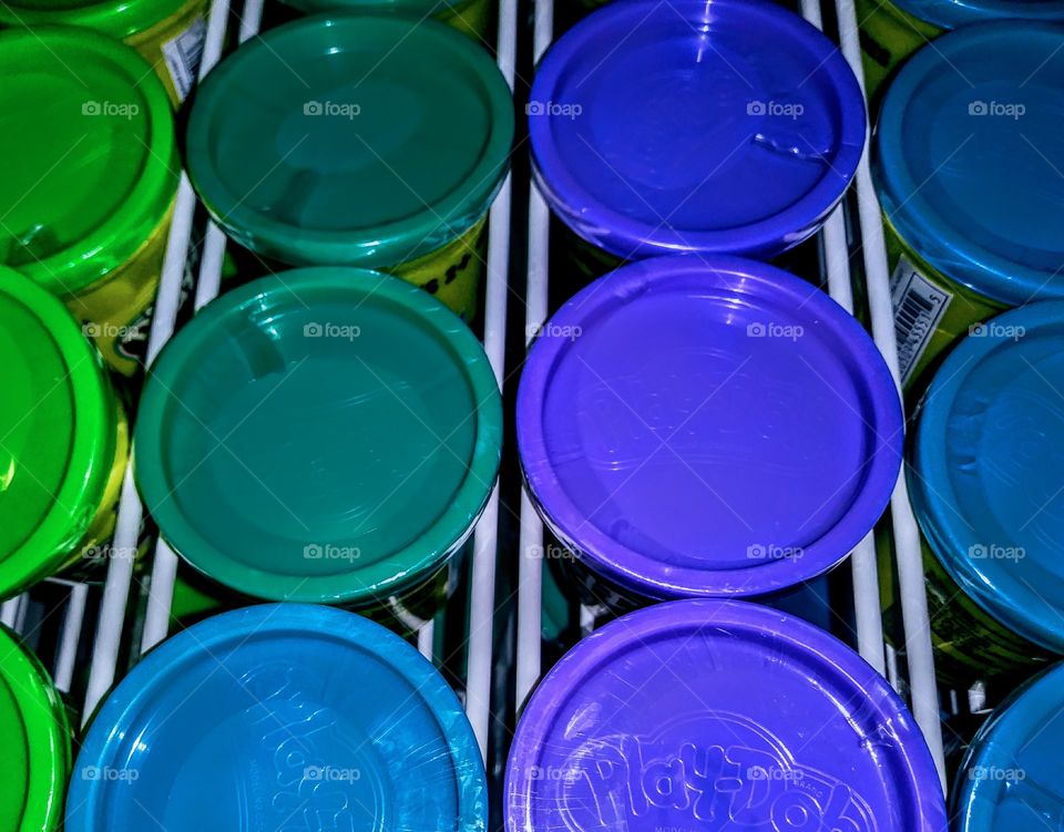 blue and green hued playdough tubs in rack