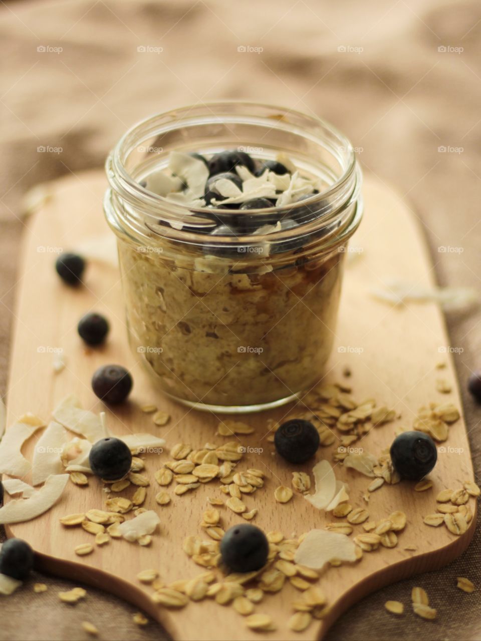 Close-up of a jar with oatmeal topped with berries and coconut flakes