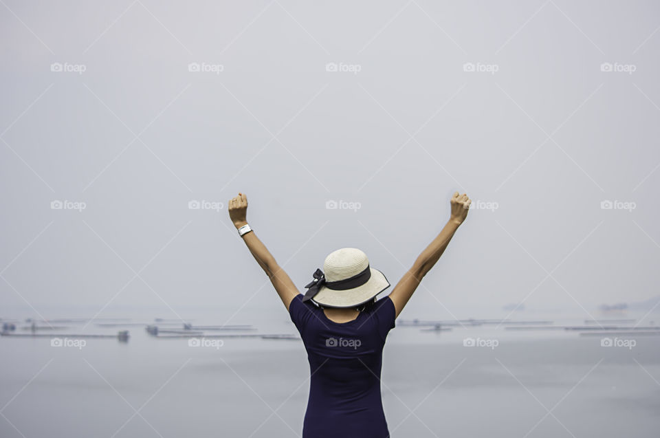 Women raise their arms Background The raft floating fish farming at Krasiew dam ,Supanburi Thailand.