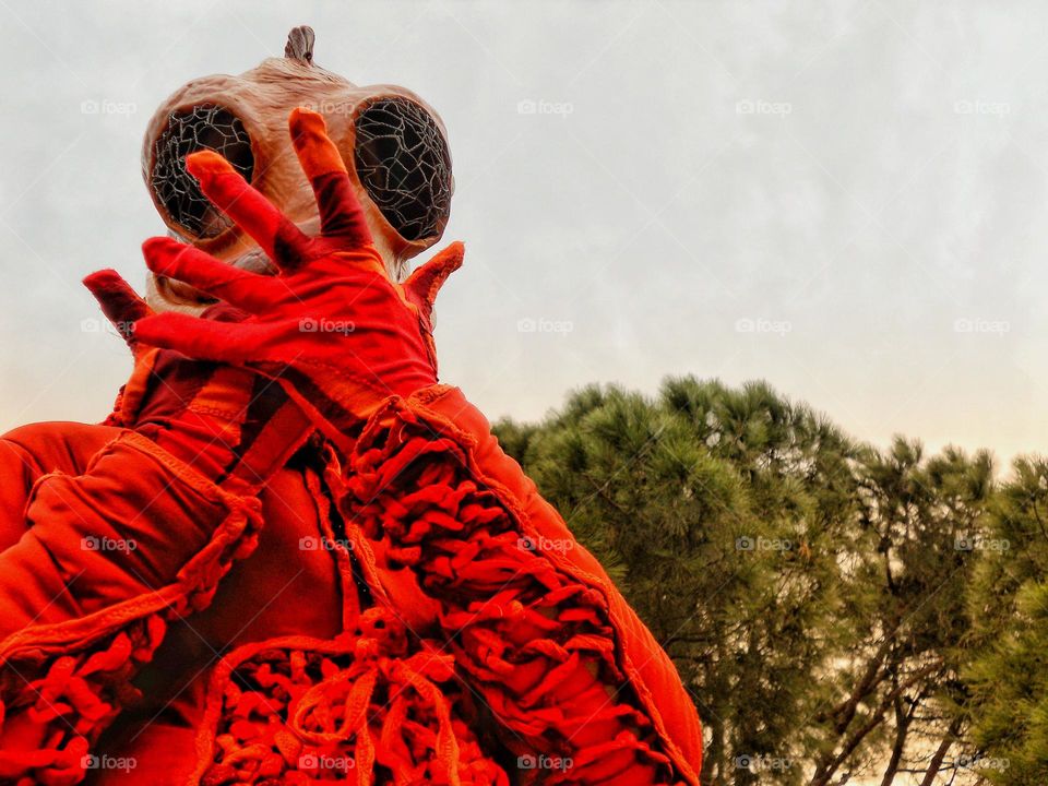 Person in what looks like an alien or bug costume and doing a gesture that looks like he is blowing a kiss to the photographer.