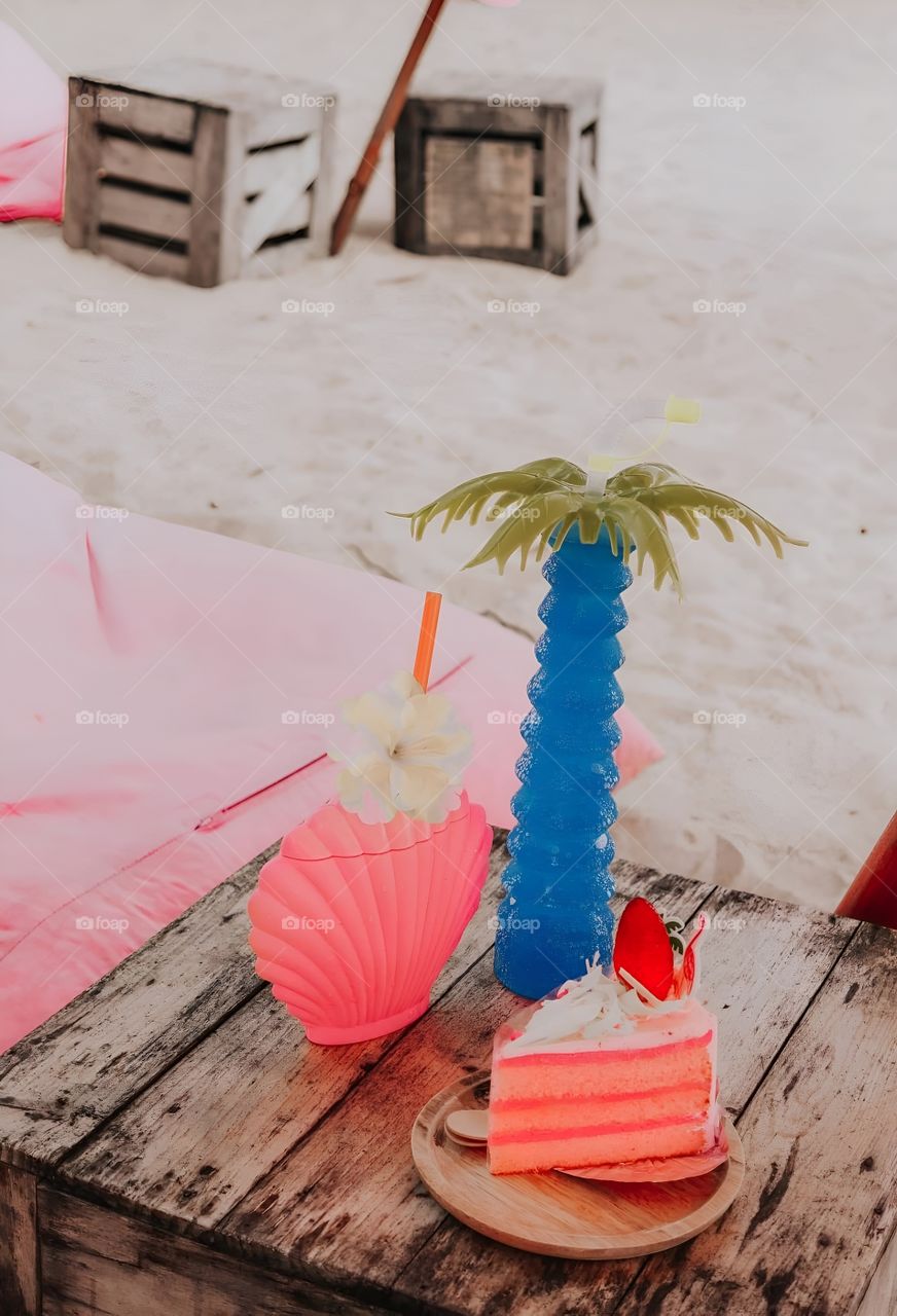Drinks in clam and coconut shaped glasses with cake