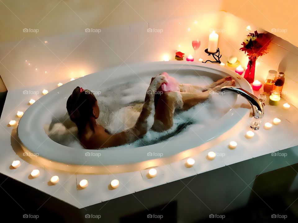 Woman enjoying a romantic candlelit bubblebath.