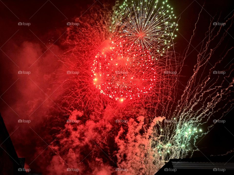 Green and red pyrotechnic fires exploding and lighting up in the sky on a wonderful night.