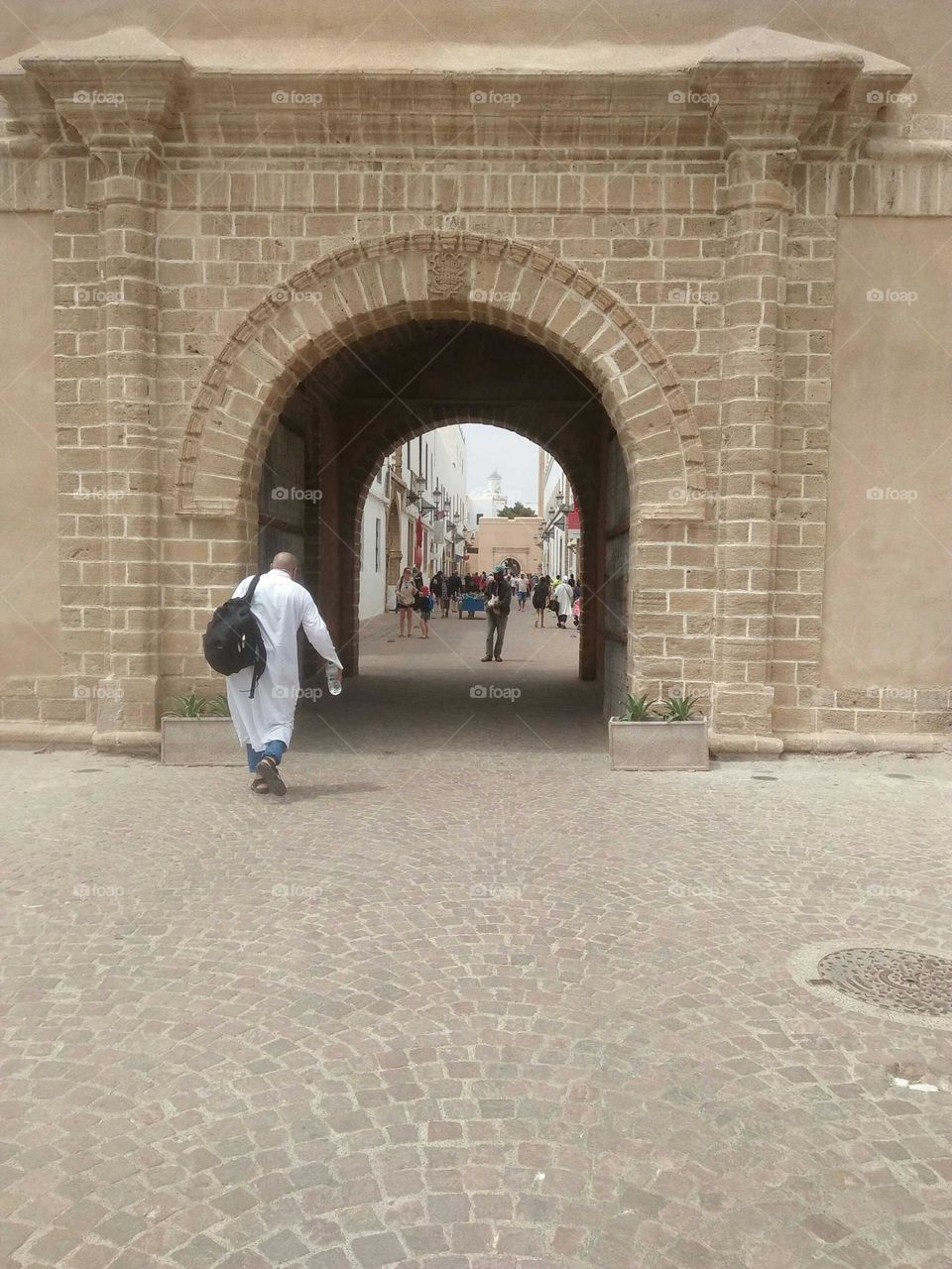 An old man walking alone in the street.