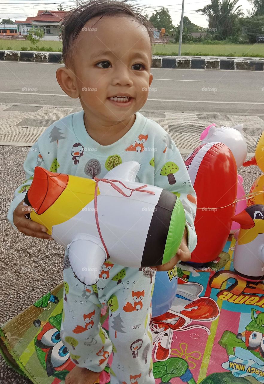 A little child looks cheerful while carrying his doll toy.