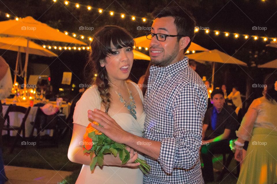 Funny young couple photo - girl wins bouquet toss at a wedding and boyfriend pushes away bouquet