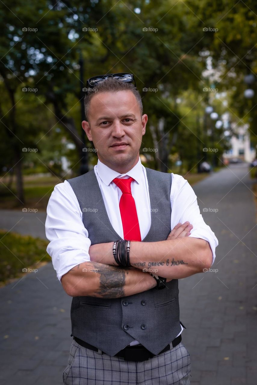 young man with tattoos walks in the summer in the park