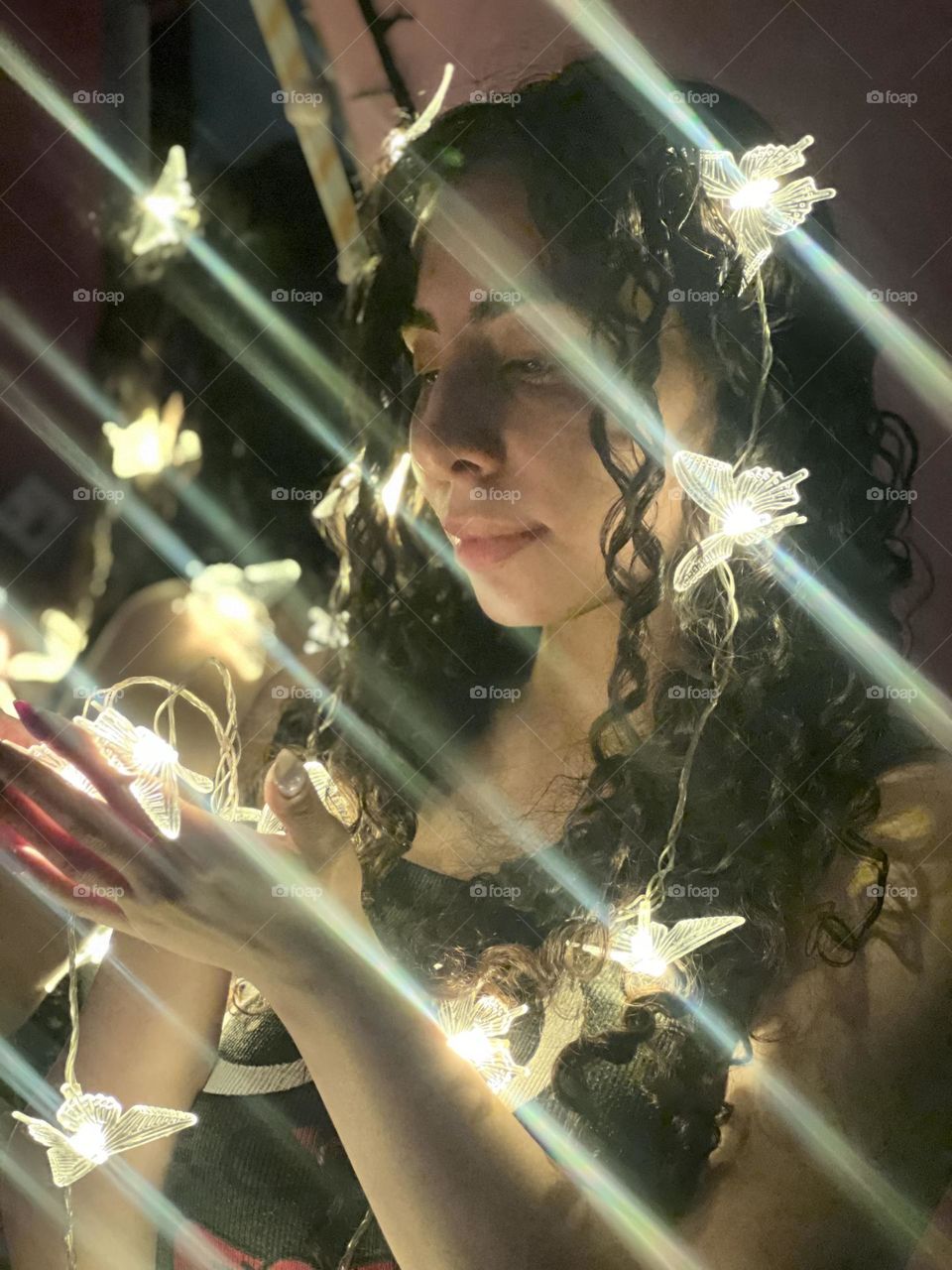 Curly-haired girl in a dark room with strands of light