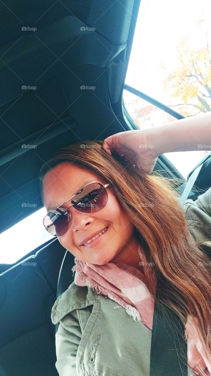 Beautiful woman in car with Ray ban glasses.