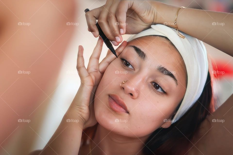 Young woman is using an eye liner