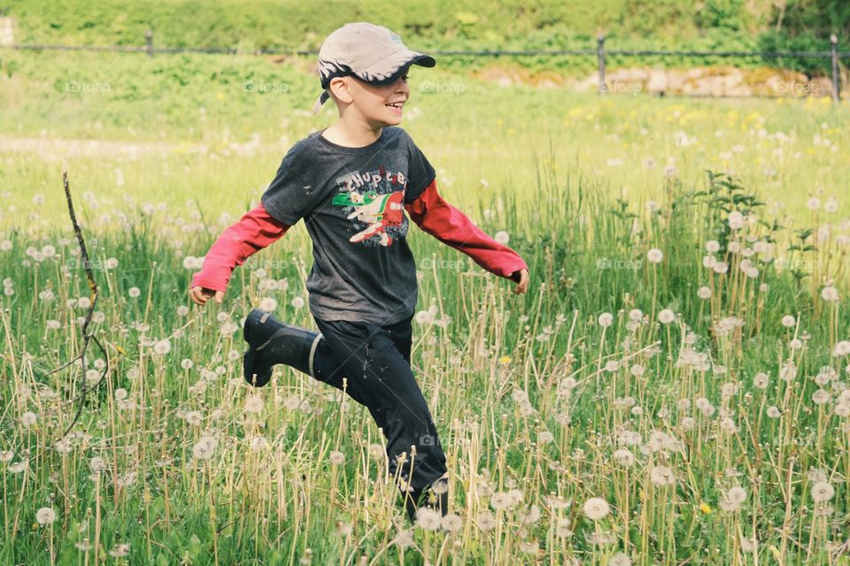 Happy boy running on a field of dandelions