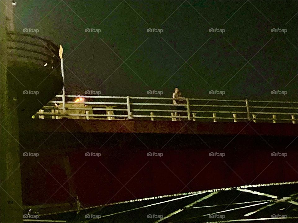 Party enthousiasts, probably guests at the „BOXHOUSE Hotel“ are now finally walking home crossing over the „Pulaski Bridge“ at „Newtown Creek“ from „Greenpoint“, Bklyn to LIC, Queens on „July 4th, 2022. Hypnotic Productions