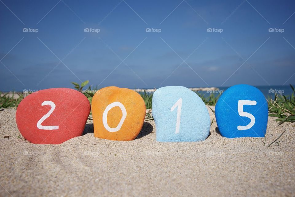 Happy 2015 on colourful stones and beach background