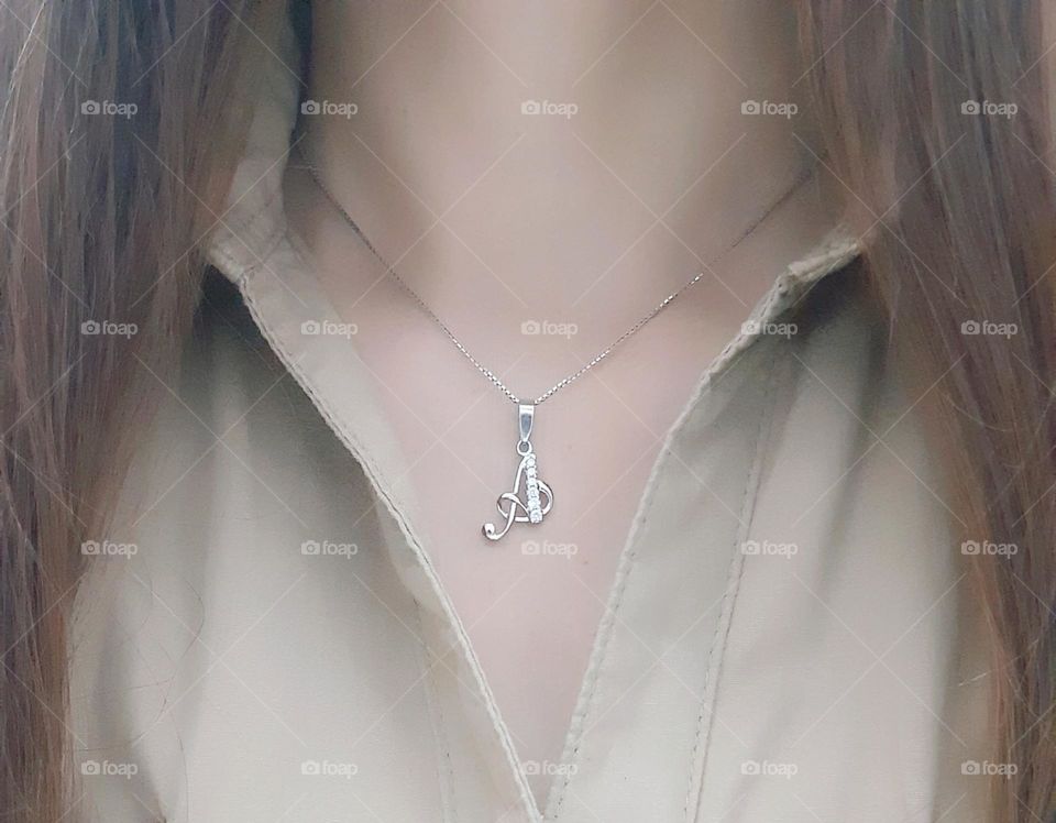 White gold necklace on the neck of the girl dressed in brown