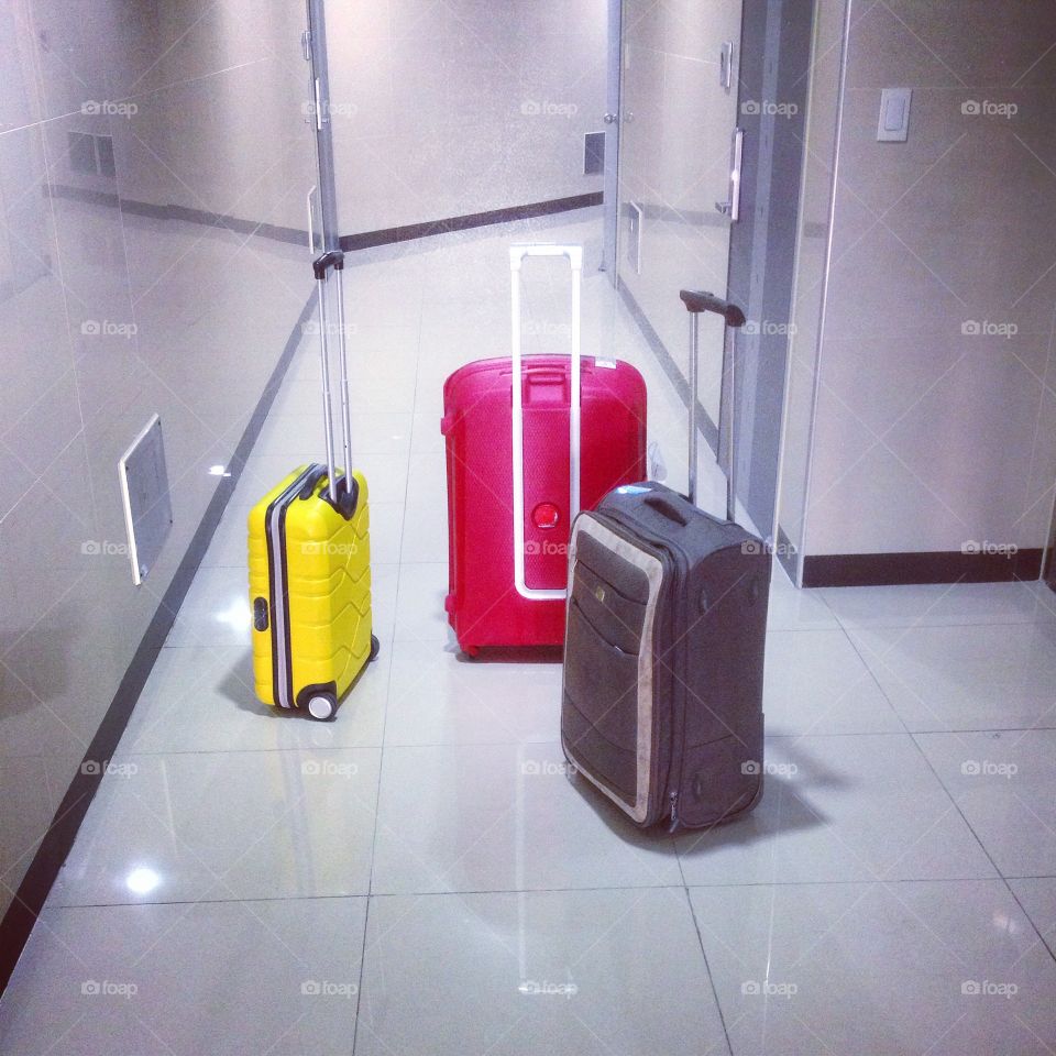 luggage waiting for travel. three suitcases in different colors and sizes standing in a corridor