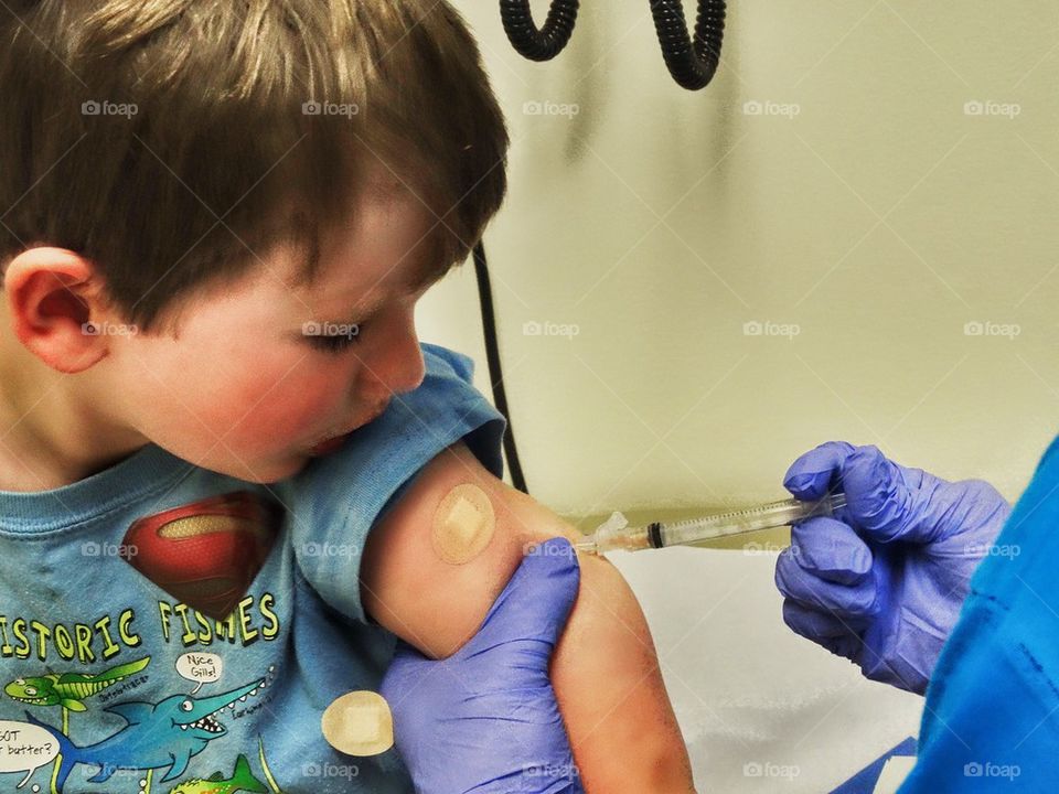 Child Receiving A Vaccination. Brave Boy Getting A Vaccination Via A Shot In The Arm

