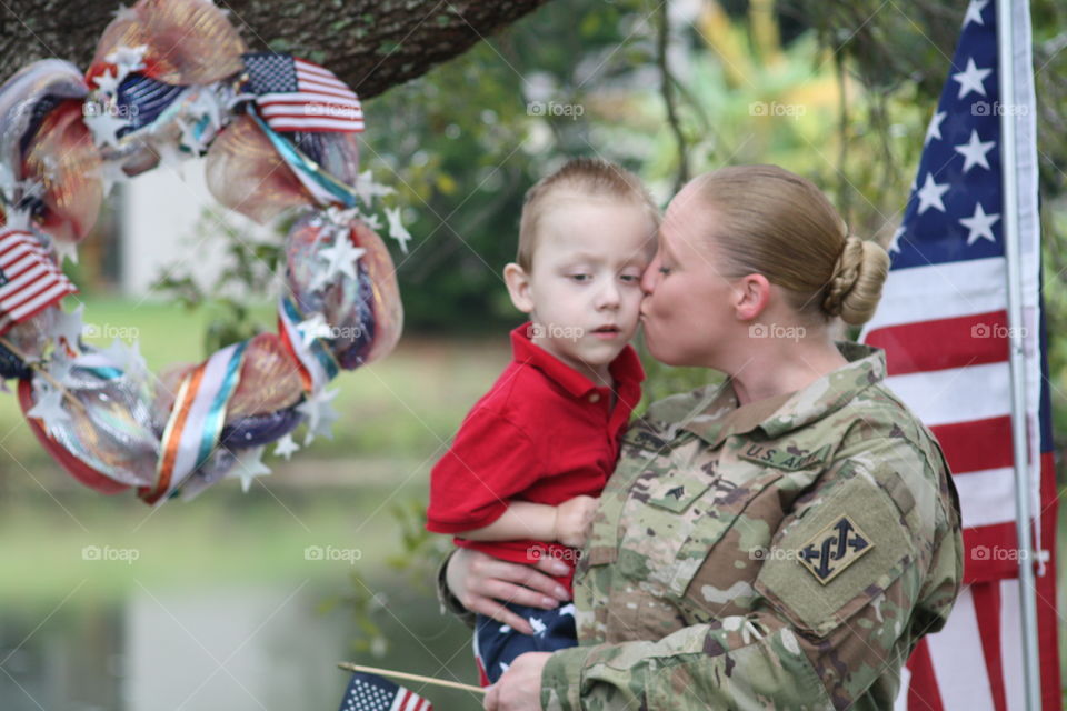 Female american soldier kissing her son on cheek