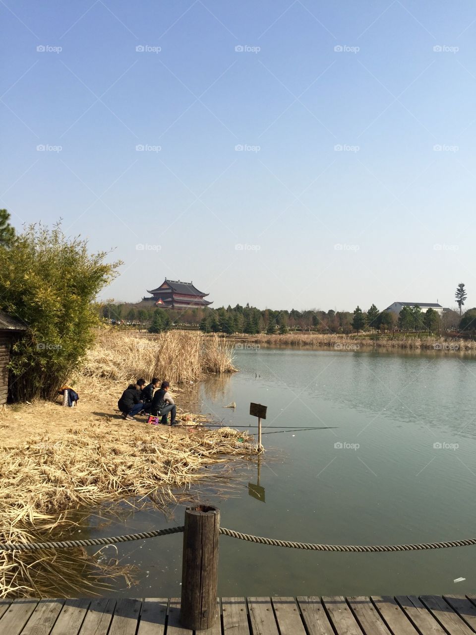 Fishermen on the lake coast with Buddhist temple on the horizon  