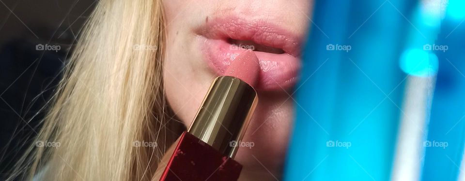 girl putting lipstick on her lips