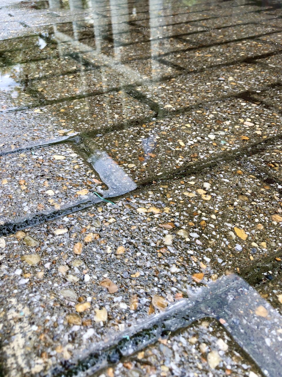 Reflection of buildings on rain puddle on pavement 