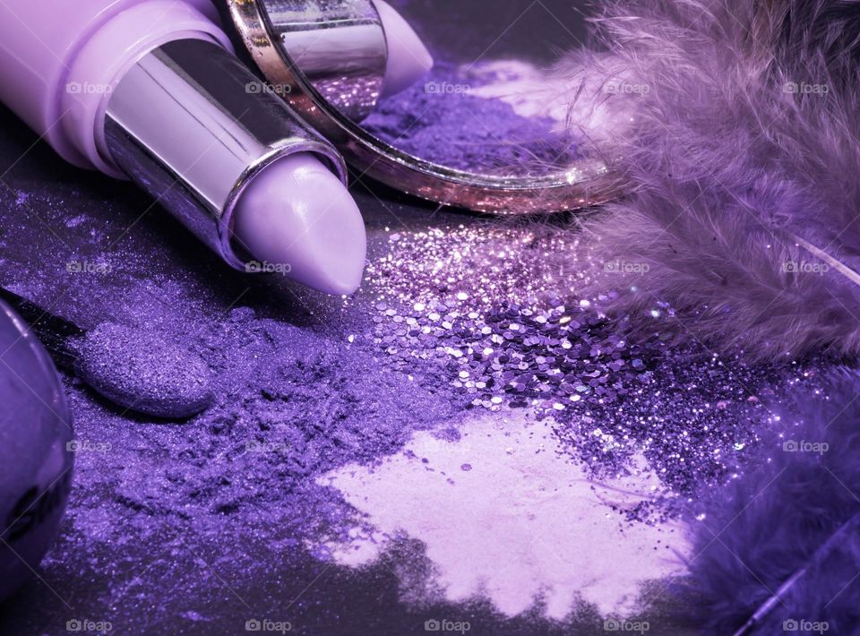 Purple glitz and glam - lipstick, glitter, eyeshadow, compact mirror and feathers in shades of indigo, lilac and lavender 