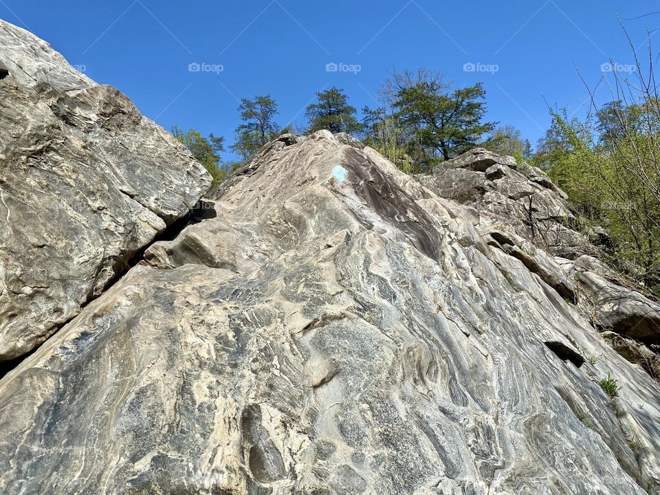 A blue blazed hiking trail going up a rock face
