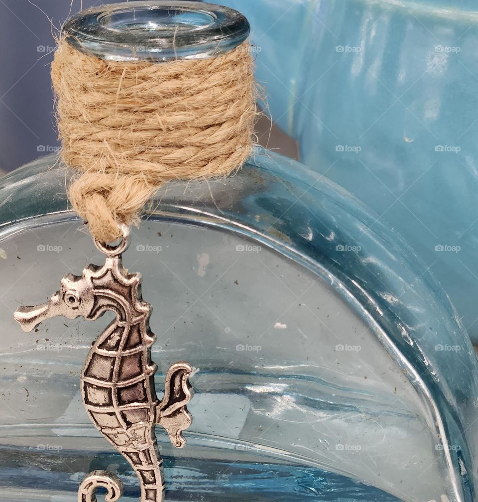 clear blue glass bottle with wrapped brown twine and seahorse charm home decor