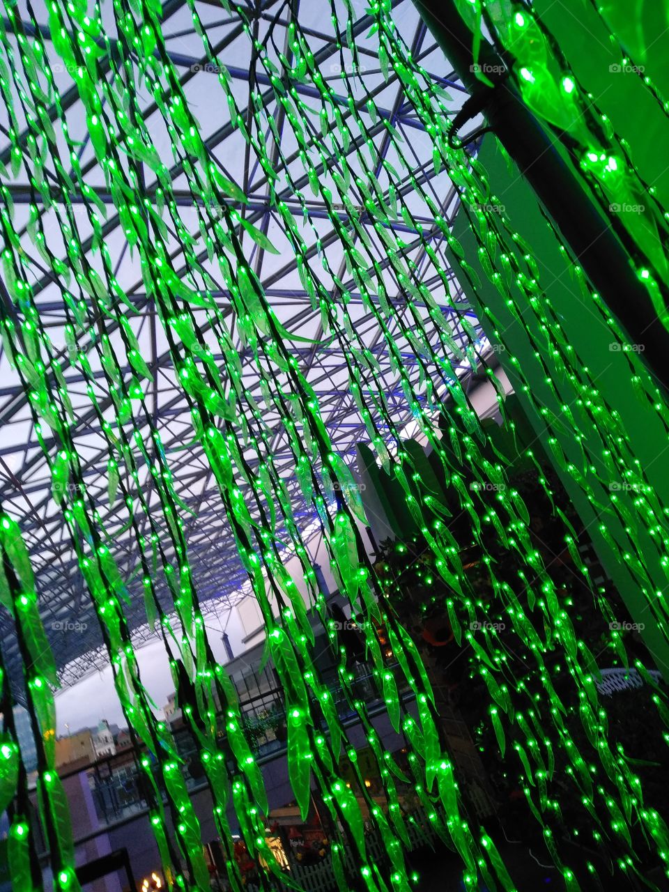 Bright green, leafy fairy lights dangling g down from the roof of Victoria Square, Belfast