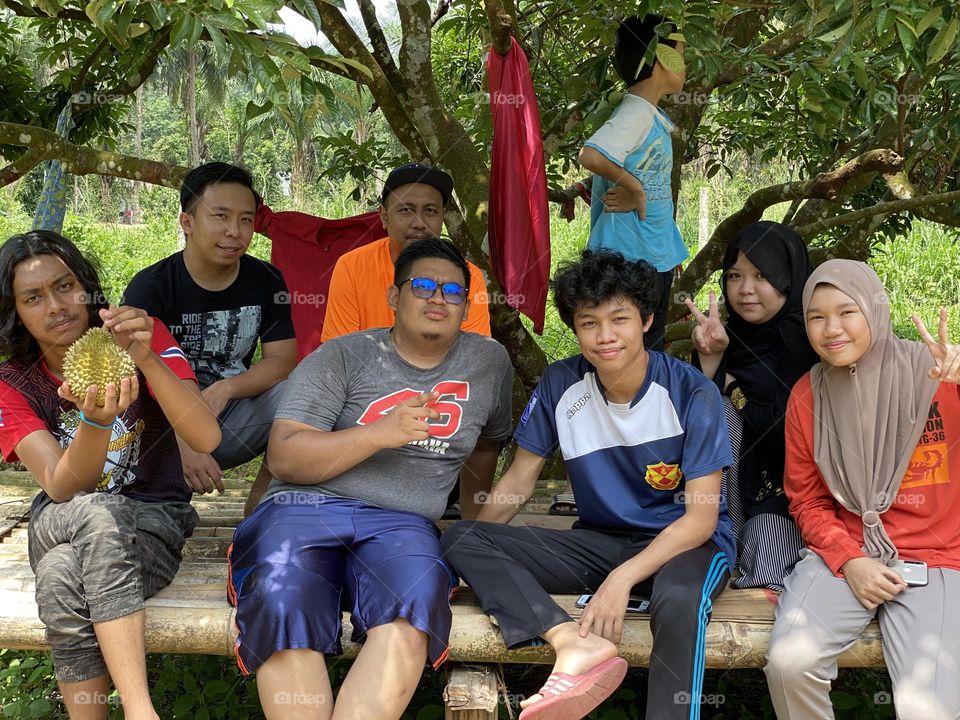 A group of young people relaxing under a tree.