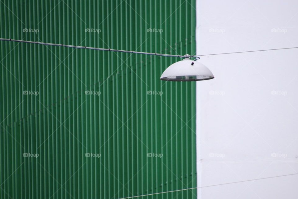 Close-up of a hanging street lamp in front of a green and white facade
