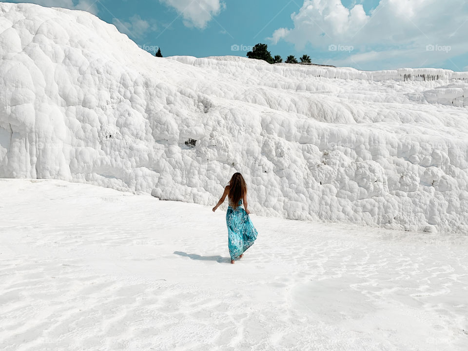 Young woman with long hair walking by white chalk mountain 