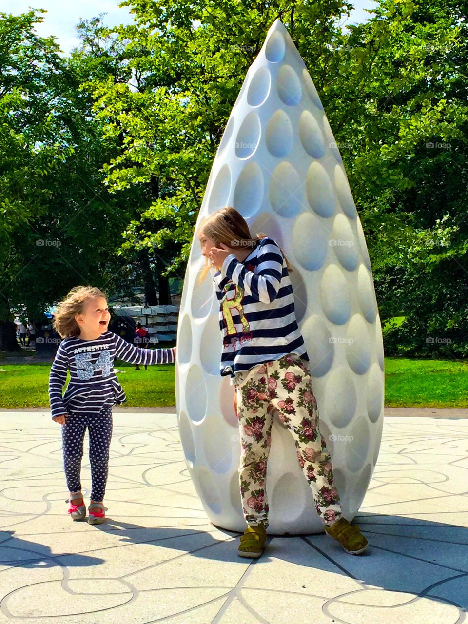 Children playing near the white sculpture in park