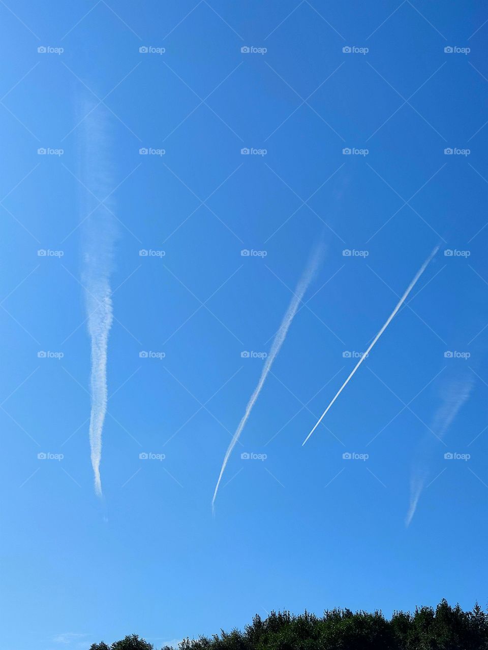 blue sky on which white traces of four planes are visible.  four white lines