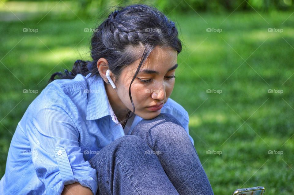 young girl with earphone and black hair in the park