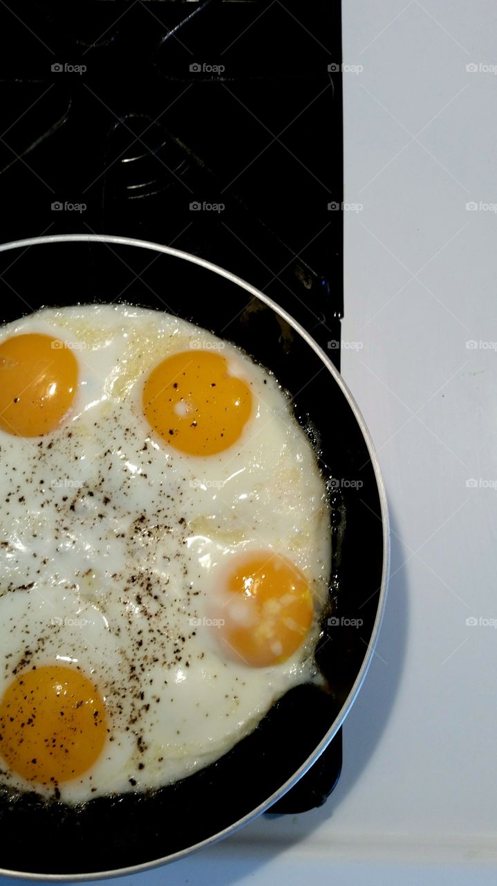 Sunnyside up eggs frying in skillet on stove top