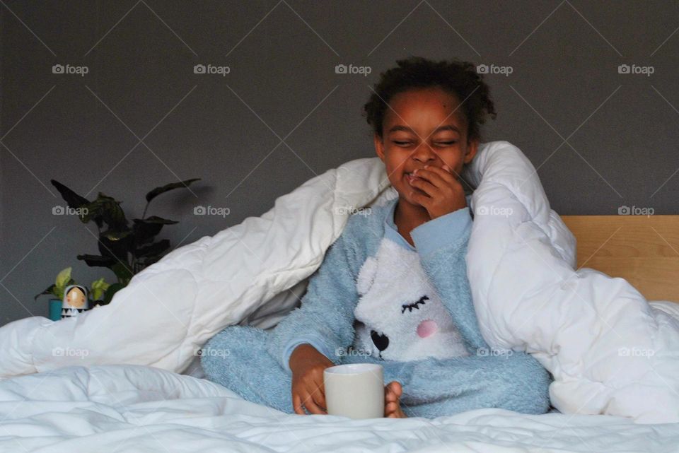 Girl drinking tea in bed and laughing