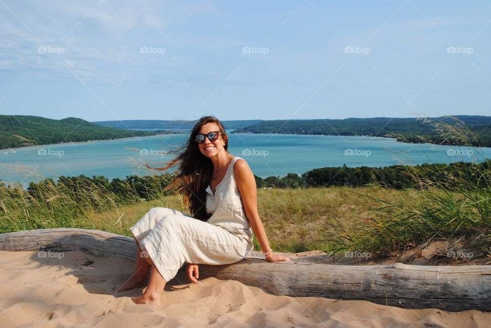 Girl sitting on log by lane Michigan.