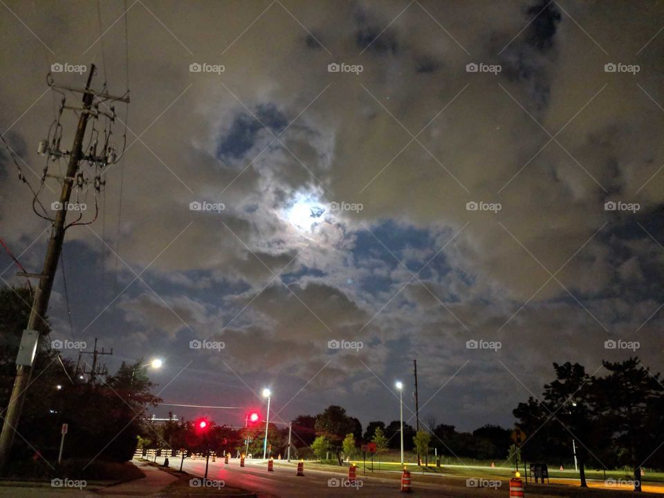 moon in clouds over road