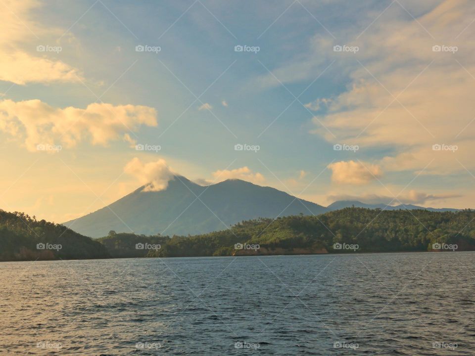 Natural scenery in the afternoon, views of green hills against the backdrop of mountains and beautiful cloud formations.