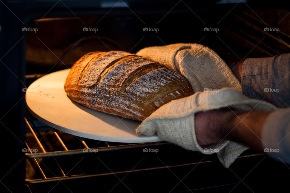 Staying at home - my husband made the most amazing artisan sourdough bread. Image of freshly baked bread being taken out of the oven. Yummy!